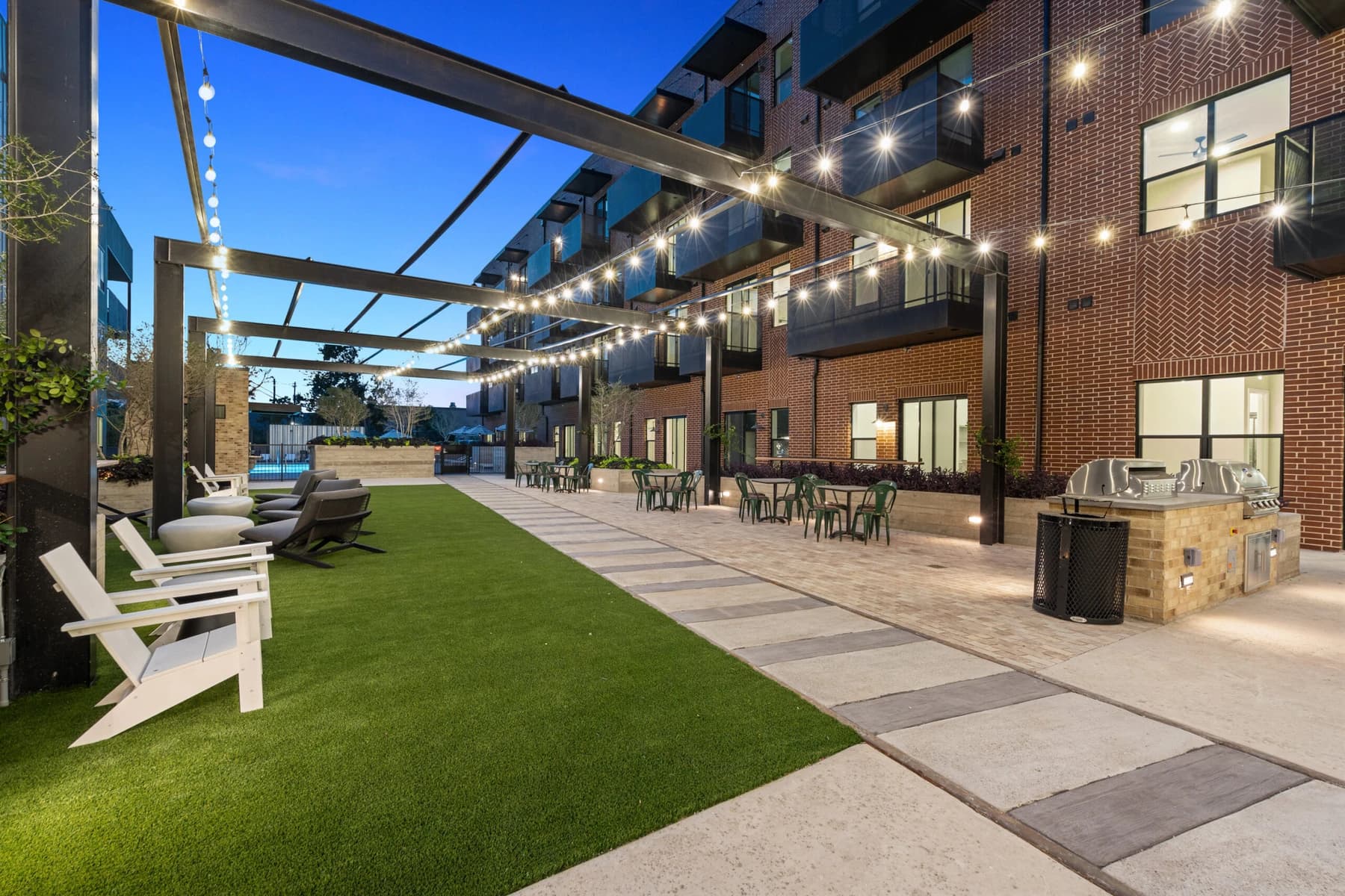 Courtyard lawn at Station at St. Elmo strung with festoon lighting at dusk.
