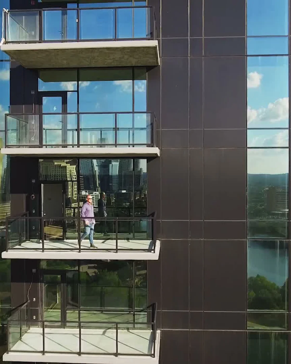 Matthew Layman on a high-rise balcony at a glass residential tower.