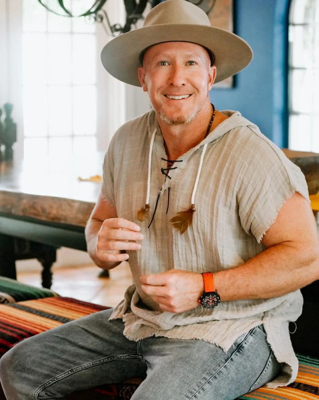Matthew Layman, luxury real estate advisor, seated in a wide brim hat in a sunlit interior.