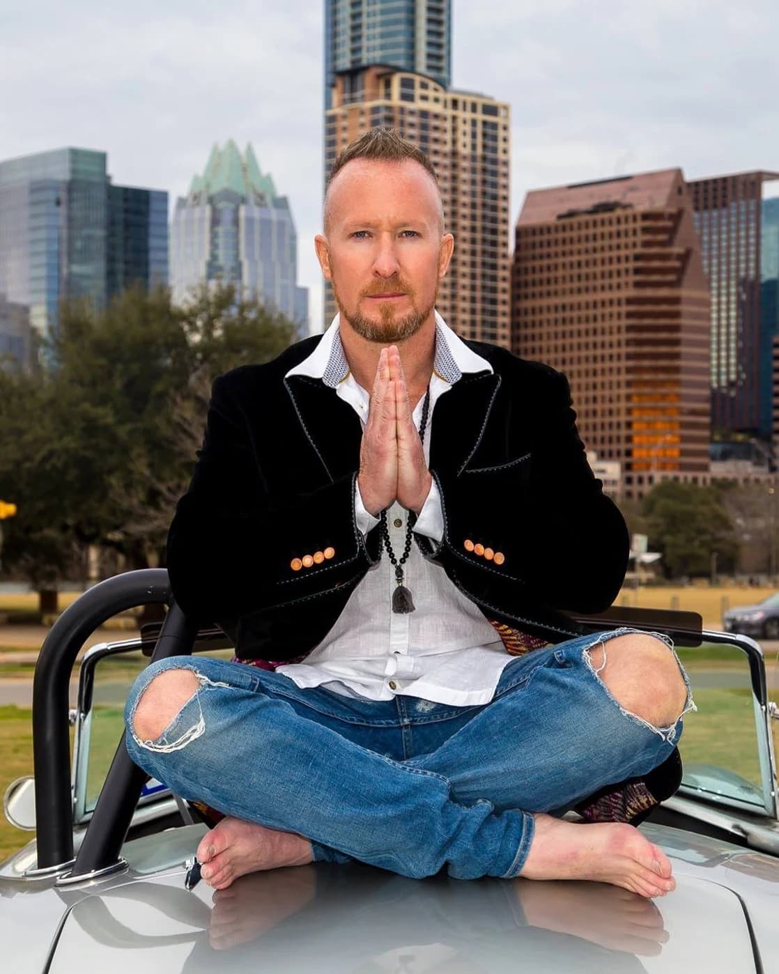 Matthew Layman seated in meditation with downtown Austin behind him.